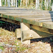 52 Steg auf Pfeilern Längsschnitt Querschnitt Der Oberbau von Stegen besteht meistens aus Holz. Bei tiefgründig vernässten Böden eignen sich dicke Pfeiler aus Rundholz oder Beton als Auflager.