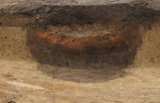 Grube mit gebrannter Lehmplatte Bef. 284 In eine zweite zylindrische Grube ist nach teilweiser Verfüllung eine Lehmplatte eingebracht und stark und über längere Zeit befeuert worden.