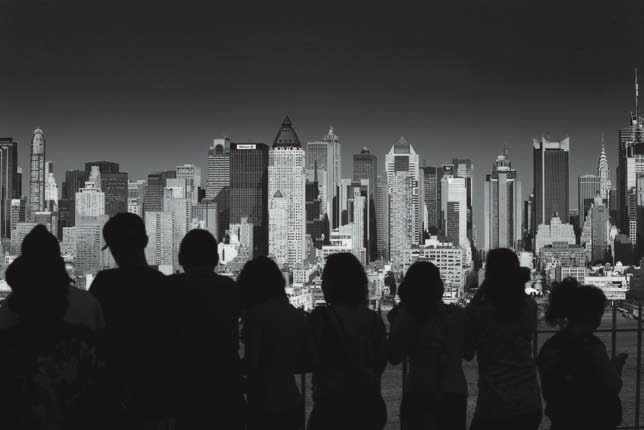 Street Photography Eine Gruppe von Jugendlichen schaut über den Hudson River auf Manhattan. Da die jungen Leute nur silhouettenhaft erscheinen, wirkt die Komposition sehr grafisch.