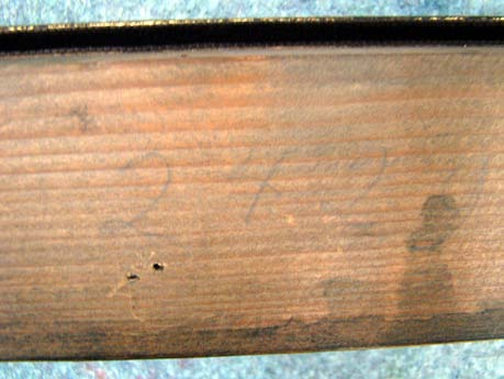 Rückseitenbetrachtung Auf dem Zierrahmen befinden sich Beschriftungen mit Bleistift und Kreide. Auf der unteren Leiste sind mit weißer Kreide die Ziffern 47.11 markiert.