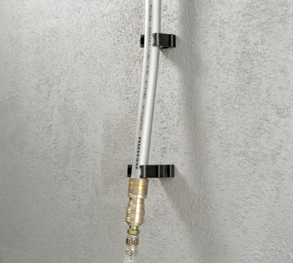 Die an der Schnellkupplung befindliche Rohrklemme wird mit einem Distanzhalter um 20 mm zusätzlich von der Wand entfernt.