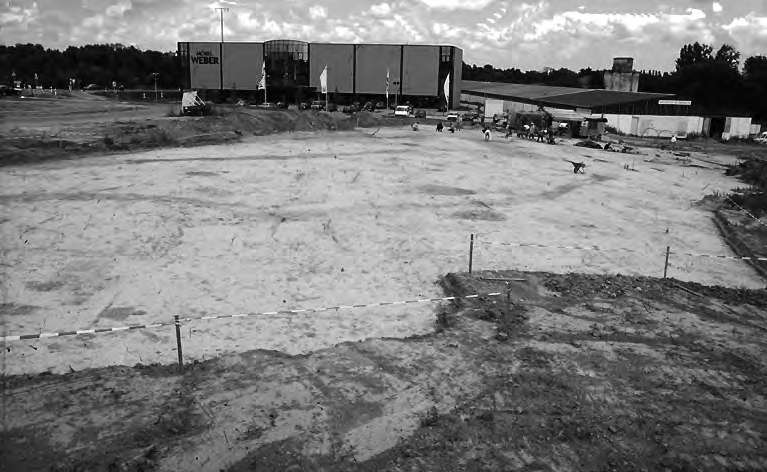 Abb. 2: Herxheim Gewerbegebiet West. Blick auf die Grabungsfläche der 1990er Grabung. Im Mittelgrund die beiden dunklen, grabenartigen Befunde des Erdwerkes.