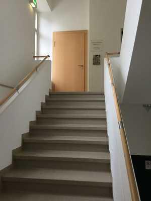 Keine Stufenkantenmarkierung, visuelle oder taktile Aufmerksamkeitsfelder vor der Treppe vorhanden. Treppe hell und blendfrei ausgeleuchtet.