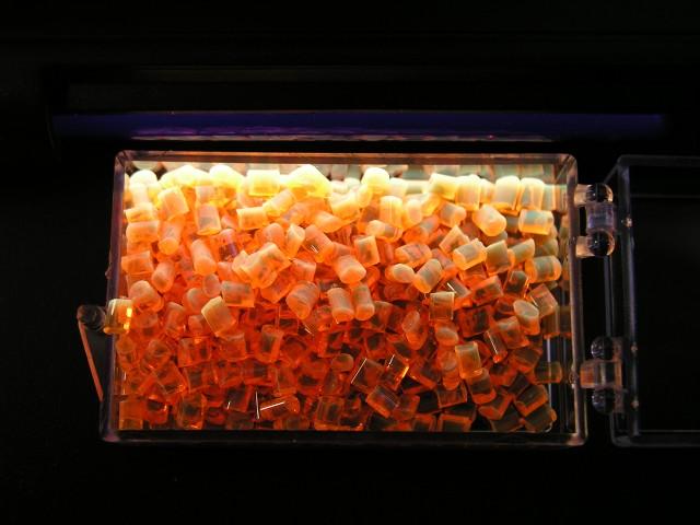 Abb. 2: Oranges Granulat leuchtet unter UV-Licht in einem