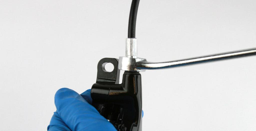 8 Verwenden Sie einen offenen 8-mm-Ringschlüssel, um die Leitungsverschraubung im Bremssattel-Leitungsanschlussstutzen zu fixieren.