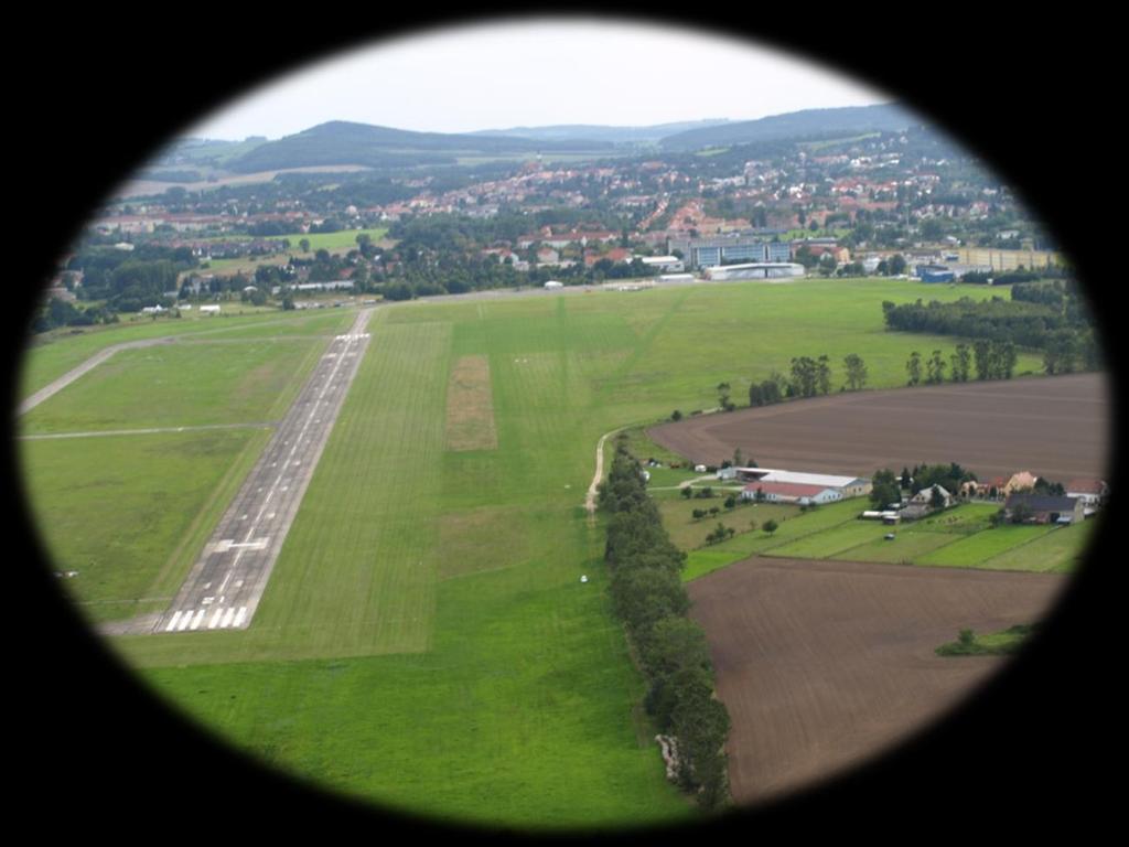 Übersicht Flugplatz (Blickrichtung Süden) Der Verkehrslandeplatz bietet zwei Landebahnen mit 1100 m Länge ( Beton 28 m / Gras 40 m breit) für Segelflieger, Motorsegler,