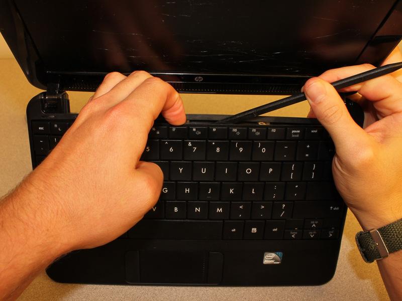 Stecken Sie das flache Ende des spudger zwischen Mitte der oberen Kante der Tastatur und dem