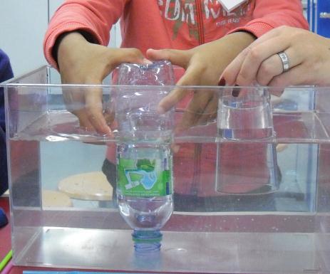 Sie drückten die Flasche unter Wasser und stellten sie dann auf, sodass die Entweichende Luft das Wasser im Glas verdrängte.