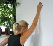 Arm maximal nach oben bringen und Handfläche an die Wand legen (leichter Druck gegen die Wand) Oberkörper nach vorn-unten