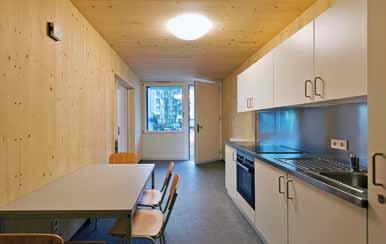 initiative bezahlbarer Wohnungsbau Mit Farben inszenieren die Architekten die Holzmodule: Grüntöne sind dort zu sehen, wo sich die Unterkunft der Natur zuwendet Die sichtbaren Holz-Innenwände haben