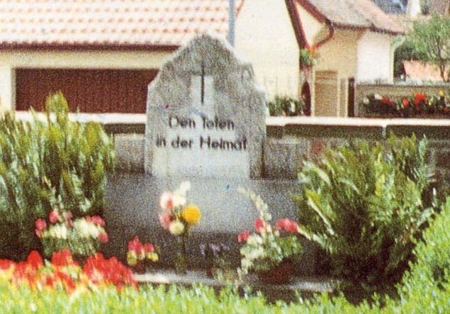 61137 Schöneck Inschrift: Den Toten in der Heimat. Standort: Friedhof in Büdesheim, einem Ortsteil von Schöneck. Errichtung: 1954.