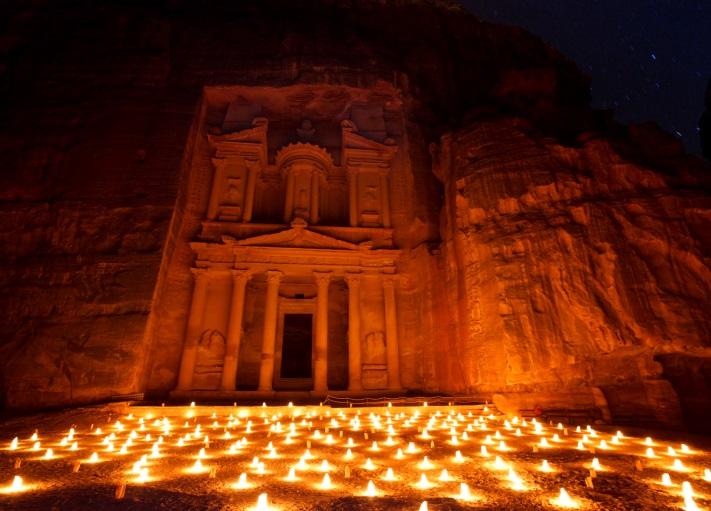 Der Zugang zur Felsstadt Petra, der Siq, wird von Kerzen beleuchtet und über Ihnen der Sternenhimmel.