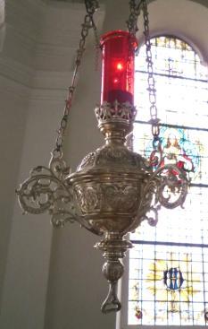 Die Ewig-Licht-Lampe, die links vom Hochaltar von der Decke hängt, erinnert Dich an