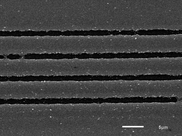 Abb. 13: REM-Bilder von Linienabträgen, geometrischer Pulsabstand 0,2 µm, Linienabstand 5 µm; links Pulsenergie 20 nj, erzielte Spurbreite ca. 1,8 µm; rechts Pulsenergie 35 nj, erzielte Spurbreite ca.