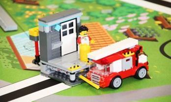2 AUFGABE Löscht den Brand, indem ihr mit dem Feuerwehrauto den gelben Hebel vor dem Haus bewegt.