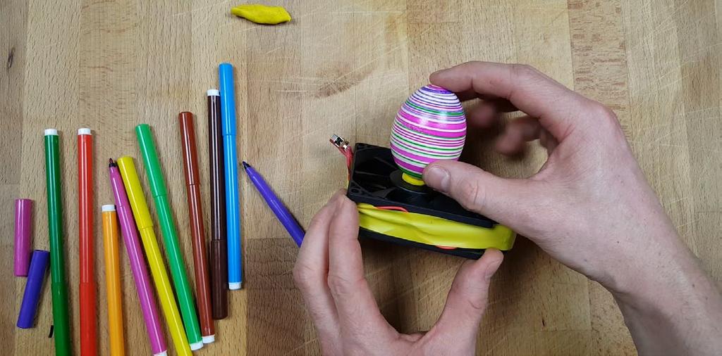 Halte einfach farbige Stifte daran. Fasse die Stifte möglichst weit hinten an und halte sie locker an das Ei.