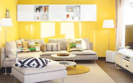 Eine gelbe Wand setzt im Wohnzimmer die