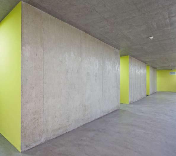 Haftarten ermöglicht. Beton an Boden, Wand und Decke prägt die Räumlichkeiten mit seinem kargen Ausdruck, kontrastiert durch das Farbkonzept und die eingebauten Holzmöbel in den Zellen.