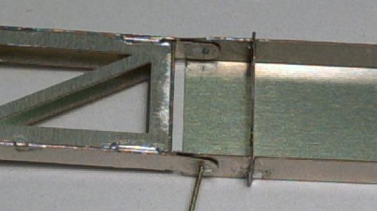 Durch das Loch im Gelenk wird ein 0,5mm Messingdraht gefädelt und von beiden Seiten verlötet. Dabei sind die beiden Blechstreifen des Gelenks leicht zusammen zu drücken.
