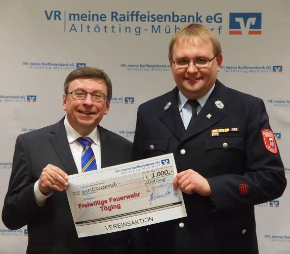 Vorsitzenden der Raiffeisenbank Reinhard Frauscher einen Scheck in Höhe von 1.000 Euro.