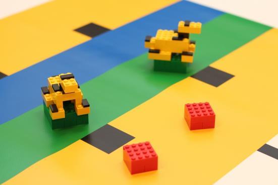 Ein Forscher oder Besucher gilt als vollständig in einem Besucherbereich, wenn der rote bzw. blaue LEGO Block nur den gelben Bereich der Spielfeldmatte berührt.