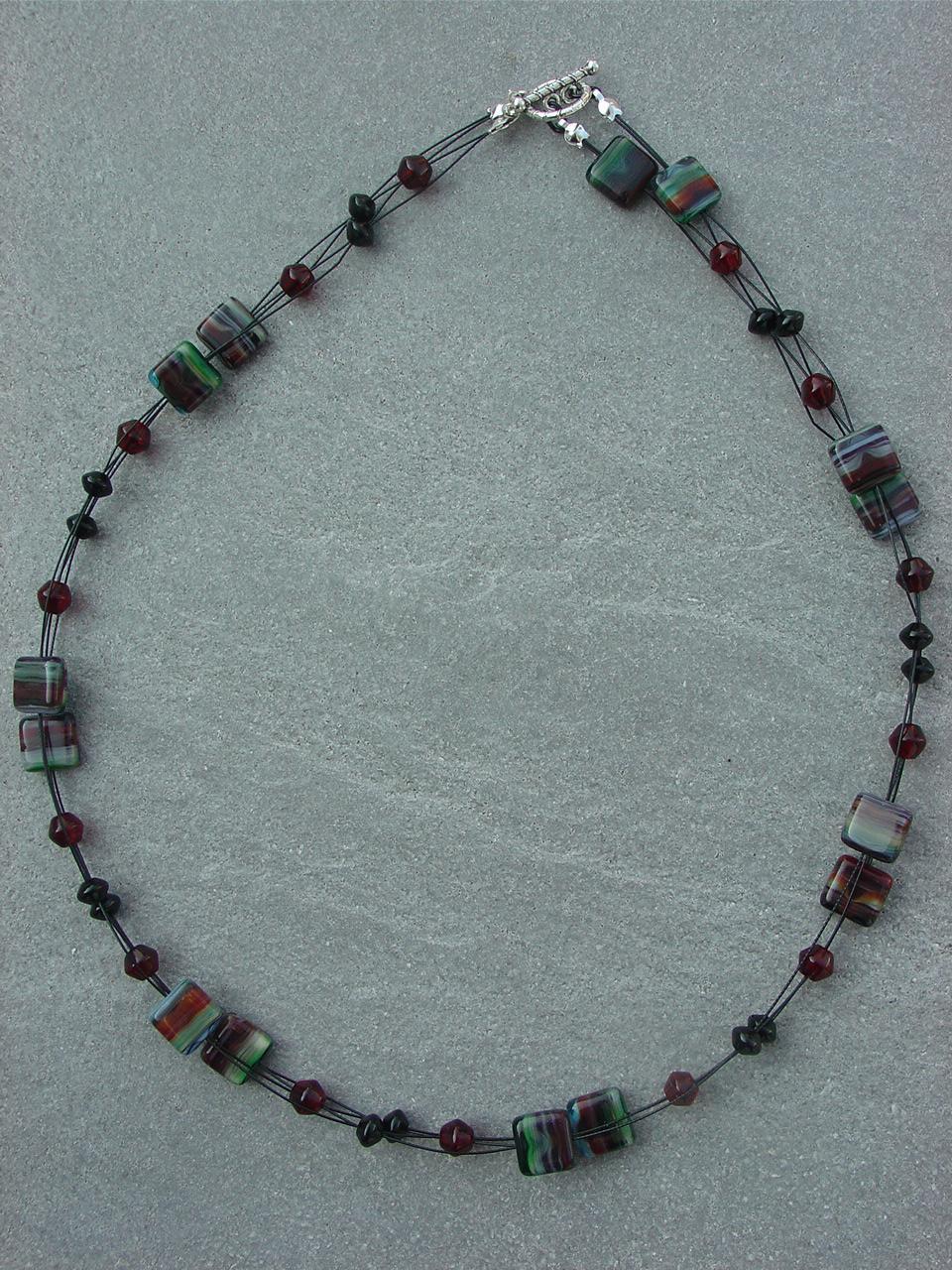 Geissblatt Einzigartige Glasquadrate, gestreift in dunklem Rot, dunklem Grün, hellem Blau, schwarz und weiß, präsentieren sich zusammen