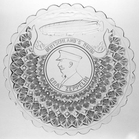 Abb. 2000-5/100 Andenken-Teller Bildnis Ferdinand Graf von Zeppelin (1838-1917) Aufschrift GRAF ZEPPELIN und oben DEUTSCHLAND' S RUHM farbloses Pressglas, D 21,5 cm Sammlung Billek