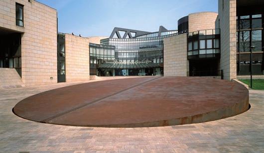 Für das große Rondell schuf der israelische Künstler Dani Karavan den Stahlbrunnen TZAPHON. Die schräg eingesetzte Stahlplatte greift nicht nur das Rund des Eingangs auf.