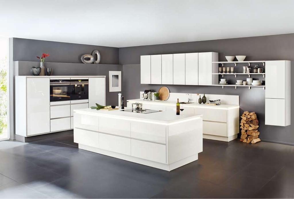 Wohnküche Grifflos-Fronten in Weiß Hochglanz, Arbeitsplatte in Weiß, ca. 245 + 515 + Insel 310 cm, ohne Dekoration, Mischbatterie, Wärmeschublade und Nischenverkleidung.