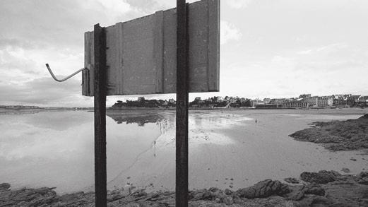Ein Küstenort in der Bretagne. Es ist Ebbe. Das Meer hat sich zu einer spiegelglatten Fläche in der Ferne zurückgezogen. zeigt keinen Film, vielmehr eine Abfolge von Schwarz-Weiß-Bildern.