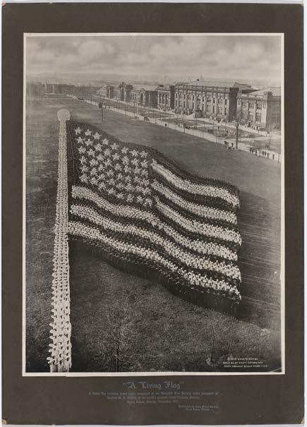 Photographie Sammlung Fleischmann 1784 MAYHART STUDIO (XX) A Living Flag, 1917. Silbergelatine-Abzug, aufgezogen auf bedrucktem Trägerkarton. Vintage.