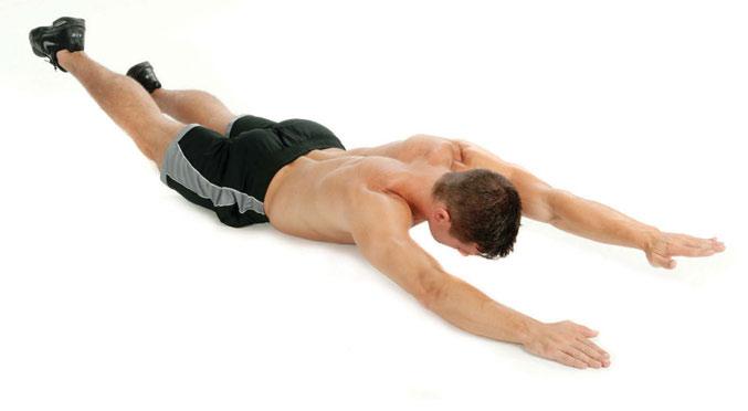2 Strecken Sie den Körper und heben Sie gleichzeitig den linken Arm und das rechte Bein. Heben Sie auch Kopf und Schultern vom Boden ab.