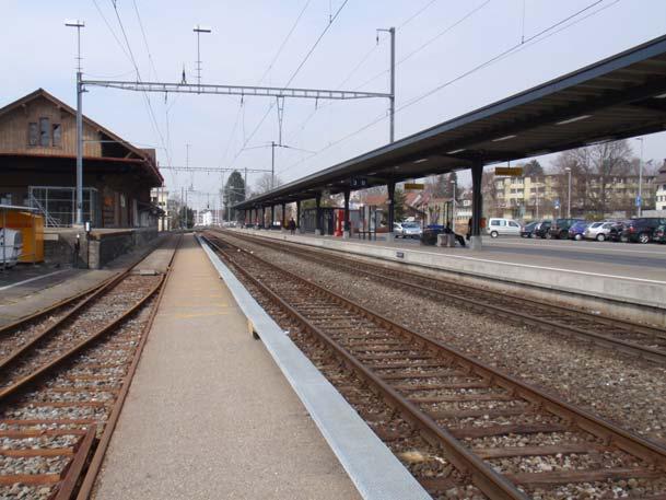 Foto 2 Gleis 1 Gleis 2 mit Einstiegshilfe Gleis 3 Regelgleis Roter Pfeil = Fahrrichtung Zug Gleisanlage in Pfäffikon ZH (Richtung Fehraltorf gesehen) Der Aussenperron Gleis 3 ist mit einem
