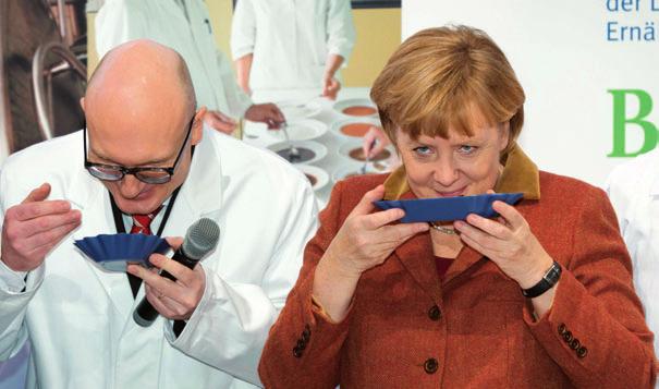 PREISE Ein Fall für die Nase: Bundeskanzlerin Angela Merkel und Mondelez-International- Qualitätsmanager Thorben Haas riechen an Kaffeebohnen aus nachhaltigem Anbau.