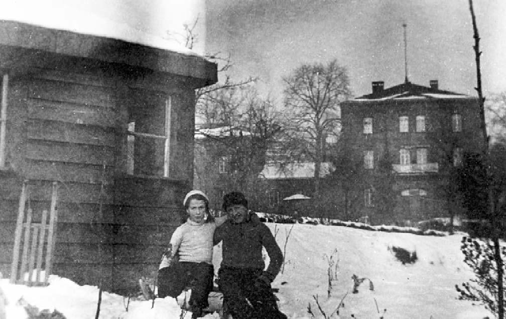 02 JAHRESBERICHT 2016 Elisabeth und Rolf Duchscherer in Ihrem Garten. Im Hintergrund ist das Gebäude der Landesheilanstalt Hadamar mit dem Haupteingang zu erkennen. Aufnahme aus den 1940er Jahren.