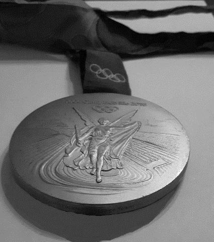 3) Das Foto zeigt eine Goldmedaille von den Olympischen Spielen 2016 in Rio. Die Medaille hat annähernd die Form eines Zylinders mit einem Durchmesser von 8,5 cm und einer Höhe von 0,7 cm.