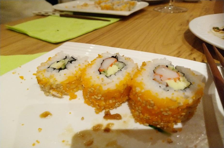 Uramaki-Sushi (umgedrehte Seetangrolle) Zutaten für 8 Rollen 600 ml Reis für Sushi 800 ml Wasser zum Kochen 8 Stück Surimi (Fischpastete) 1 Stück Gurke (oder Avocado) 4 EL Sesamkörner (oder