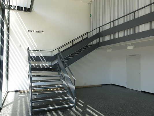 Die Treppe hat gerade Läufe. Die Treppe hat einen einseitigen Handlauf. Treppe vom Foyer zum Studio West im 1.
