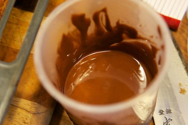Dann tauche ich die Nussecken rein. Bald ist der Schokoladenspiegel im Becher zu niedrig, und so verteile ich auf den restlichen Nussecken die Schokolade in Spritzern.