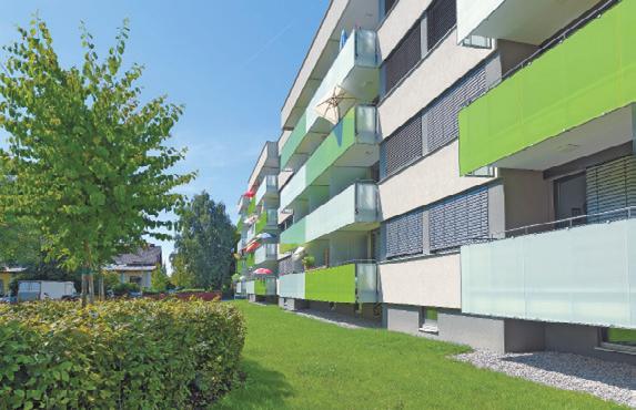 In einem der zwei Häuser mit leistbaren Mietwohnungen sind die gläsernen Brüstungen der Balkone und die hölzernen Wohnungstüren rot, im anderen grün.