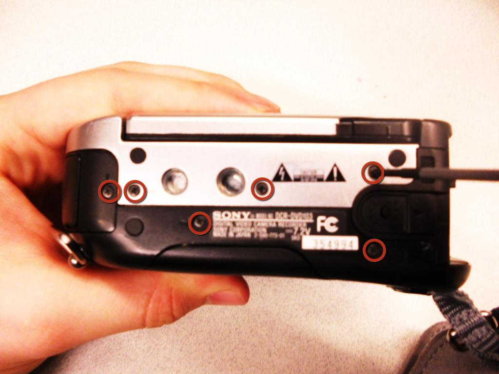 Schritt 3 Außenabdeckung Entfernen Sie die (6) 4.5mm Schrauben an der Unterseite des Sony Handycam, die mit kleinen Kreisen gekennzeichnet sind.